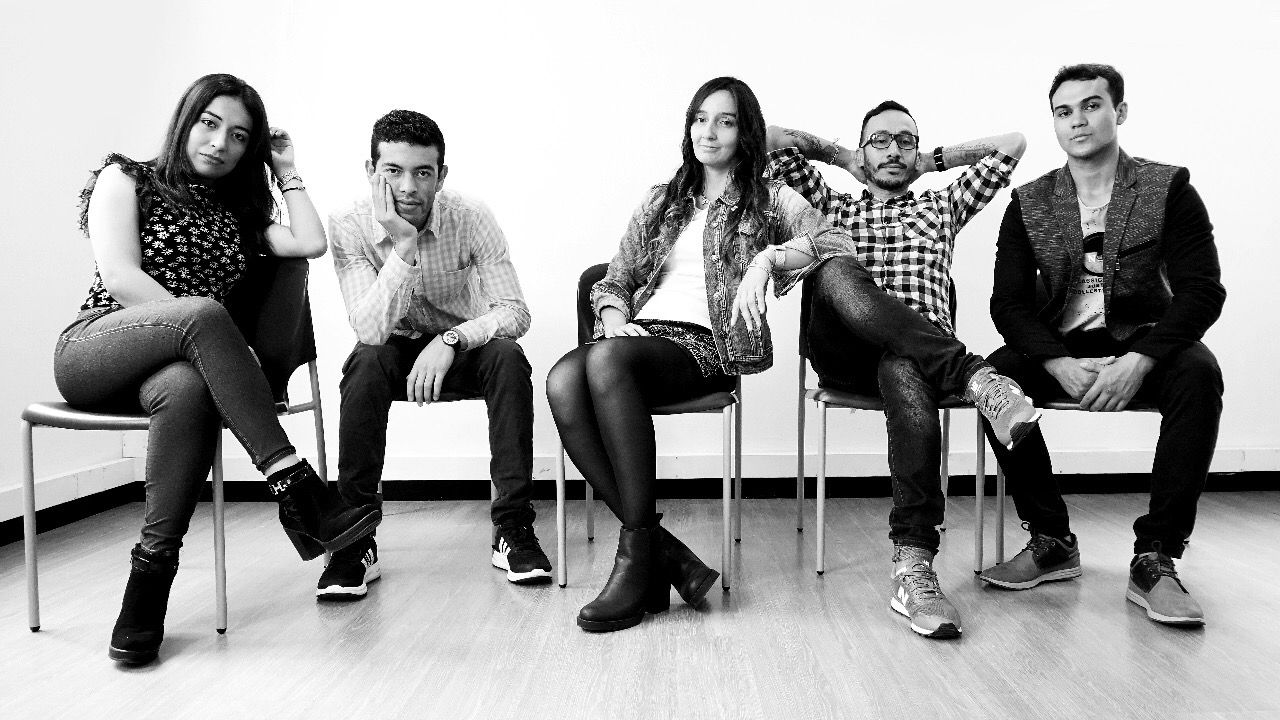 men and women on chairs in a line looking at camera